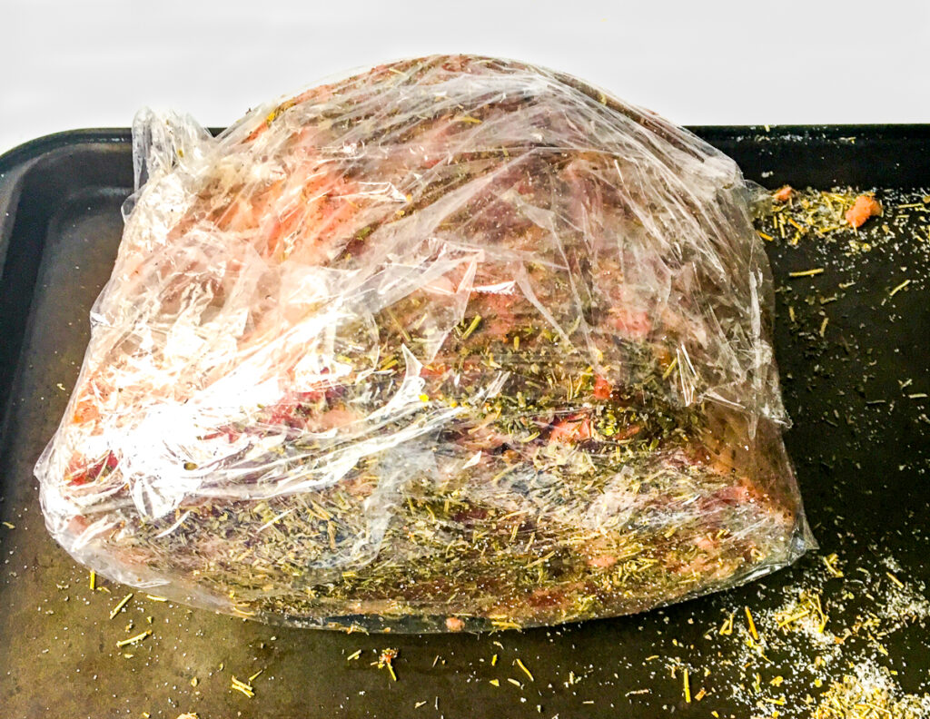 raw prime rib with spice rub on it and in a plastic bag