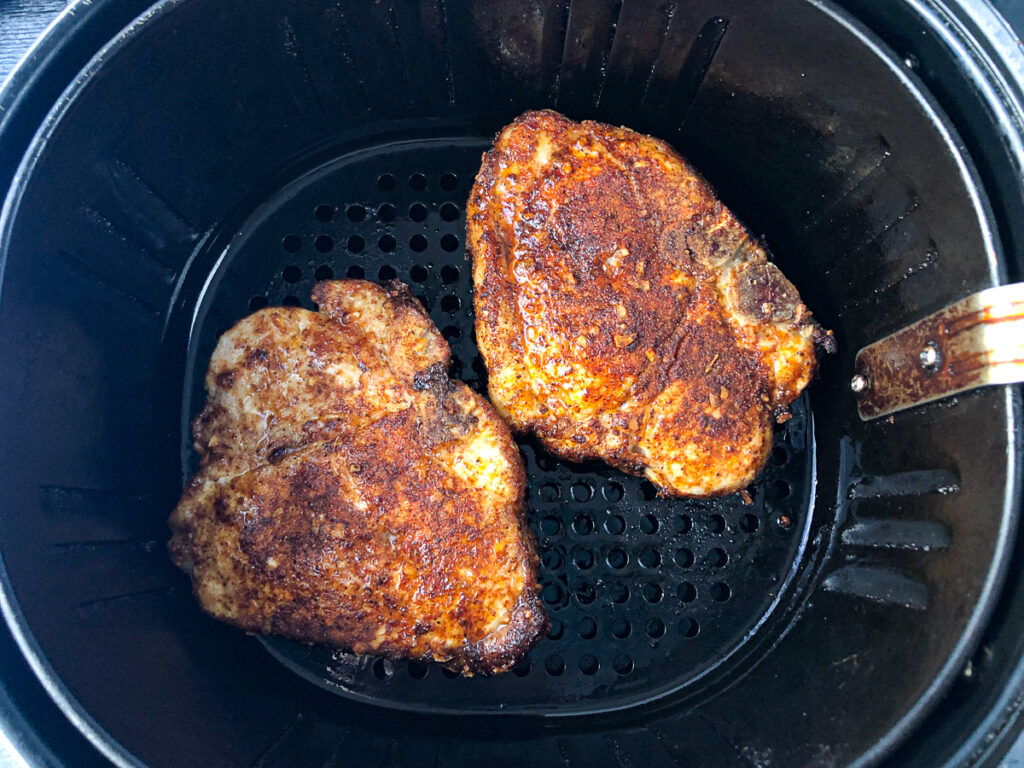 air fryer basket with cooked pork chops