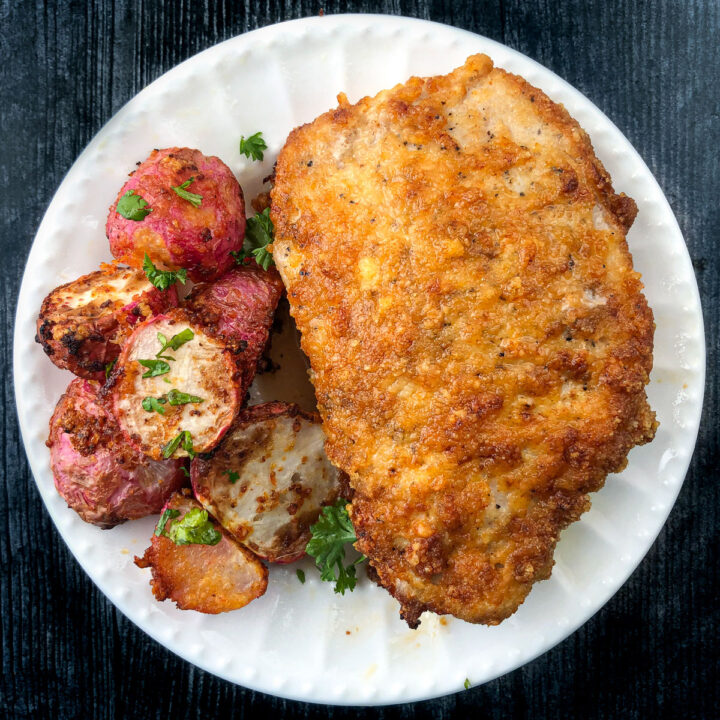A white plate with breaded keto pork chop and roasted radishes made in air fryer.