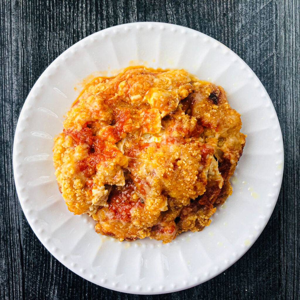 A white plate with a serving of Keto Chicken Parmesan casserole.
