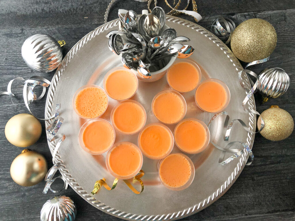 aerial view of a silver platter with orange creamsicle jello shots and silver and gold ornaments