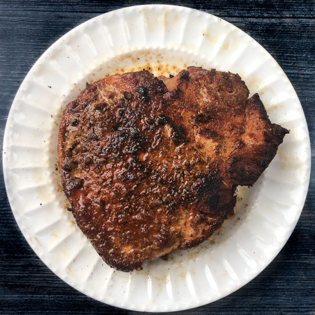 A white plate with smoked pork chop.