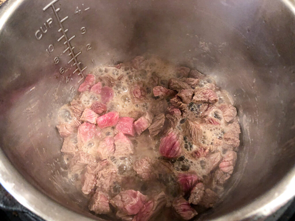 instant pot with beef cubes browning using the saute function