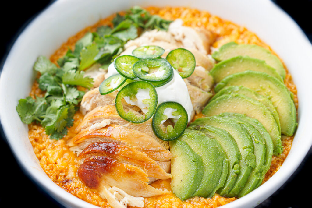 closeup of a Mexican enchilada bowl with sliced chicken on top and other Mexican toppings