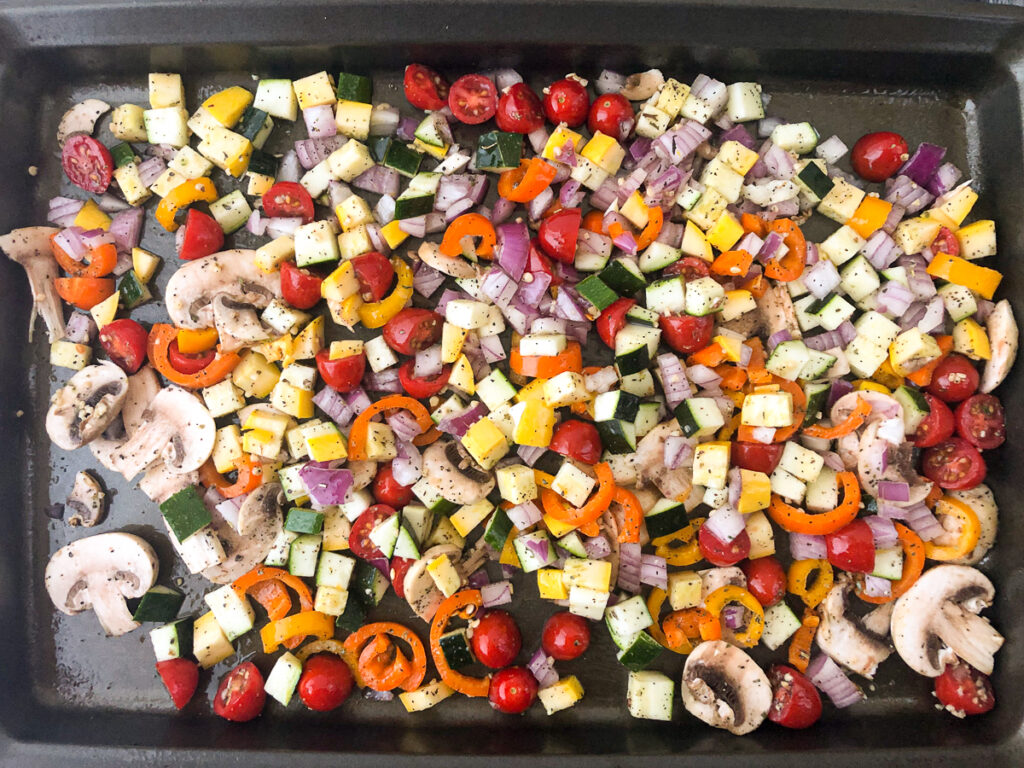 roasted vegetables on a cookie sheet ready to go in the oven