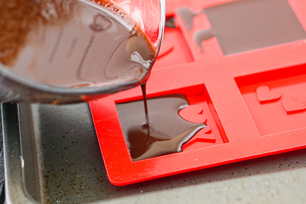 pyrex measuring cup pouring melted chocolate in mold