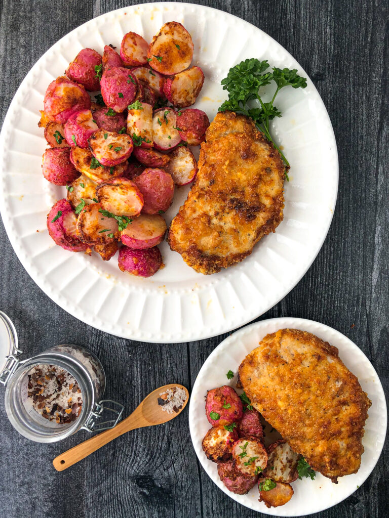 2 white plates with air fryer breaded pork chops and roasted radishes