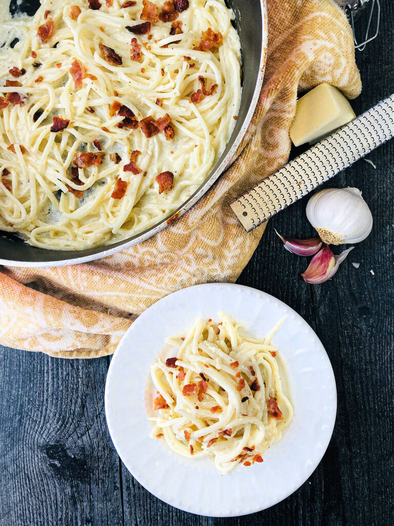 white plate and pan with keto linguine carbonara and garlic