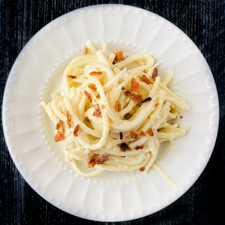 white plate with palmini noodles with carbonara sauce