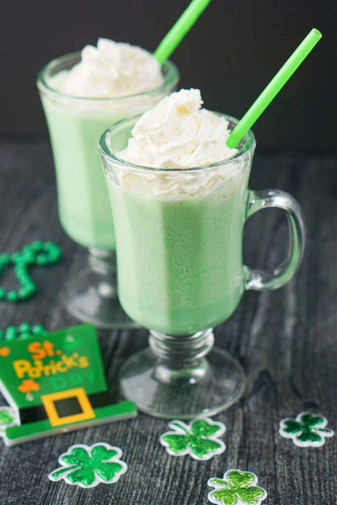 2 glass mugs with green keto mint shake with green straws and st. Patrick's day decorations