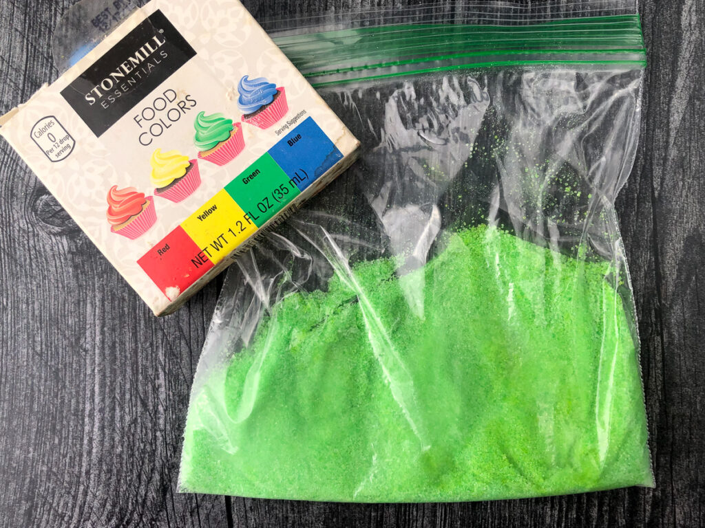 container of food coloring and a baggie of homemade green sugar free sprinkles