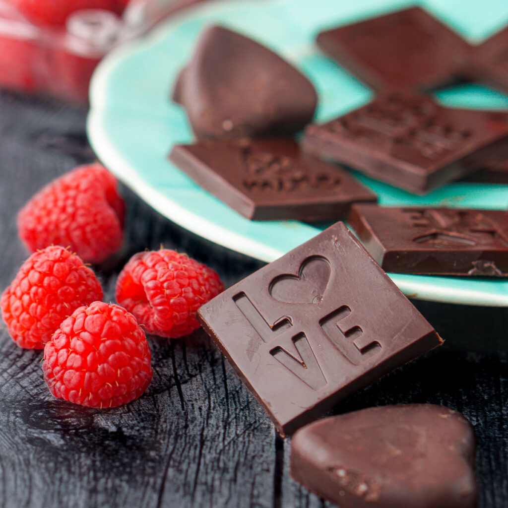 Aqua plate with keto chocolates and a few fresh raspberries.