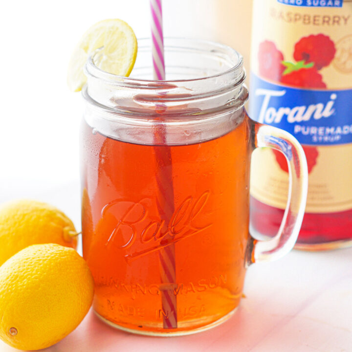 jar glass with keto raspberry tea with fresh lemons and Torani bottle