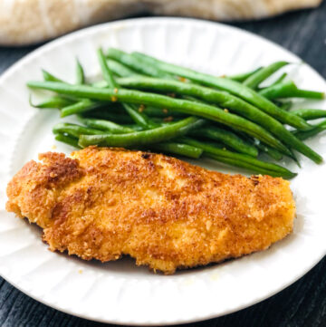 white plate with coconut crusted chicken and green beans