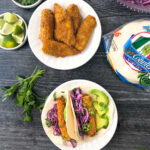 2 plates of keto air fryer fish tacos and dishes of toppings and text