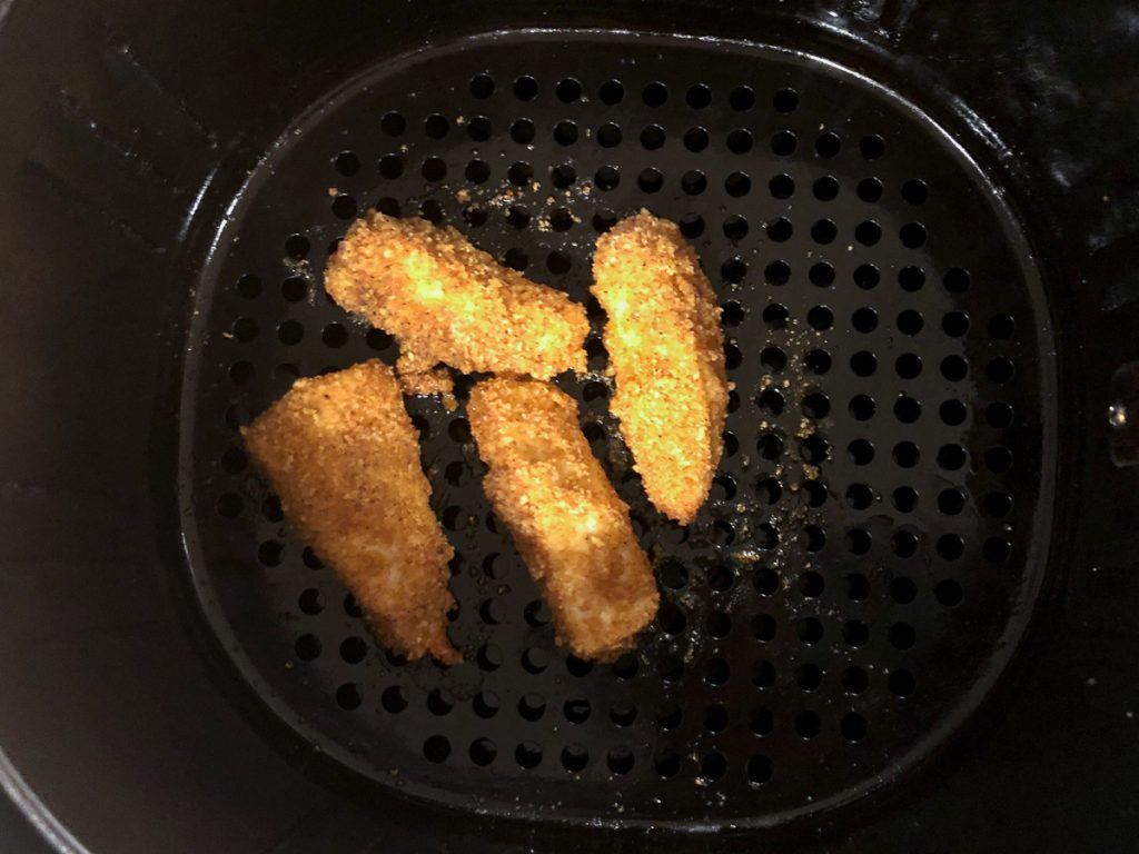 air fryer basket with fried tilapia pieces