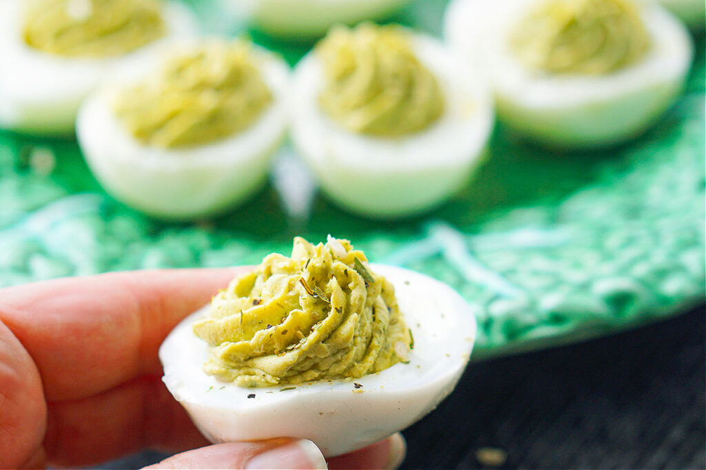fingers holding a low carb green goddess deviled egg