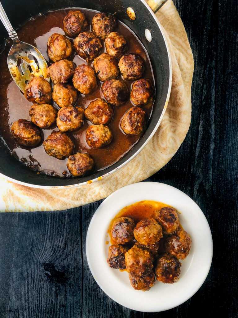 aerial view of a pan and whit plate with keto bbq meatballs