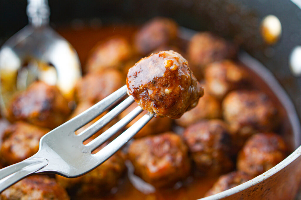 a fork with a keto meatball in bbq sauce