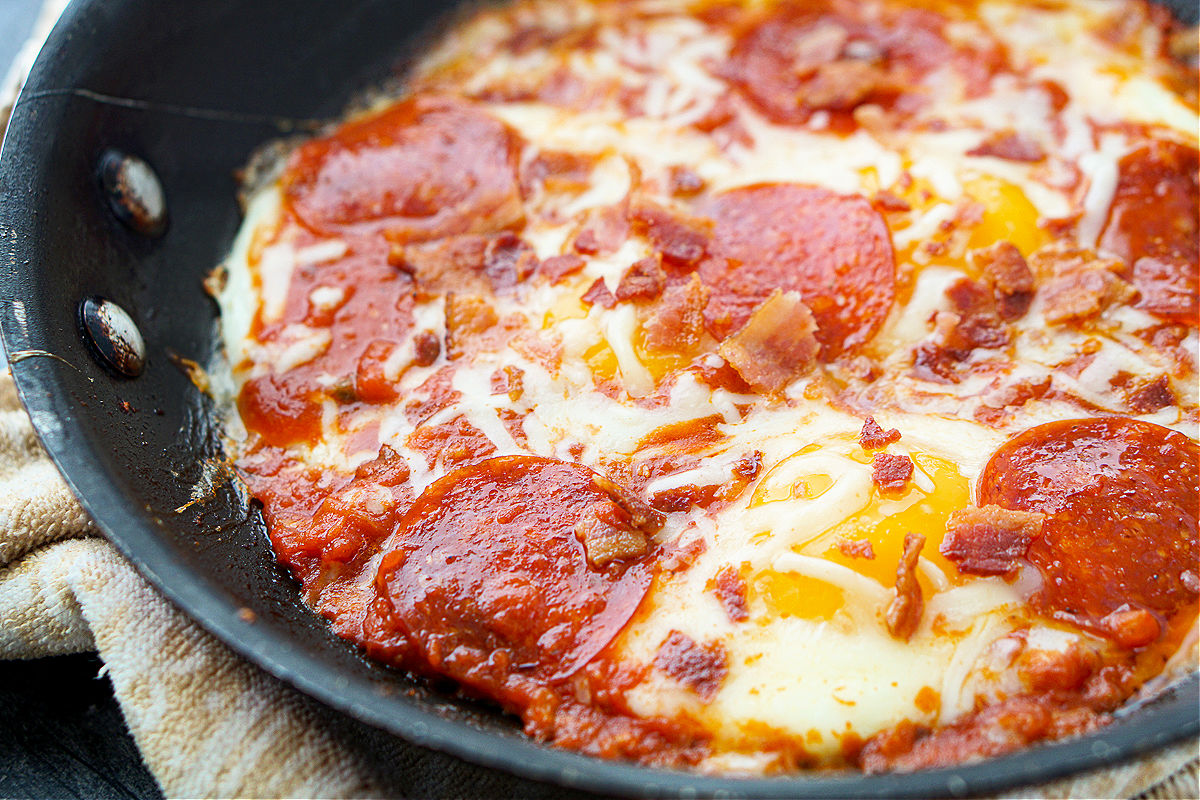 closeup of a skillet with pizza eggs with pepperoni