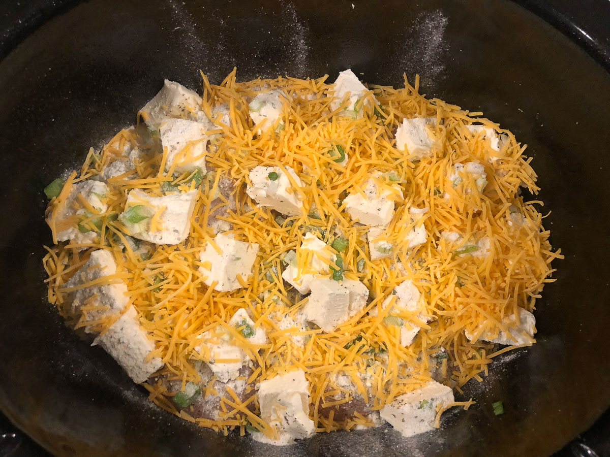 crock with raw chicken, cream cheese, ranch, green onions and cheddar