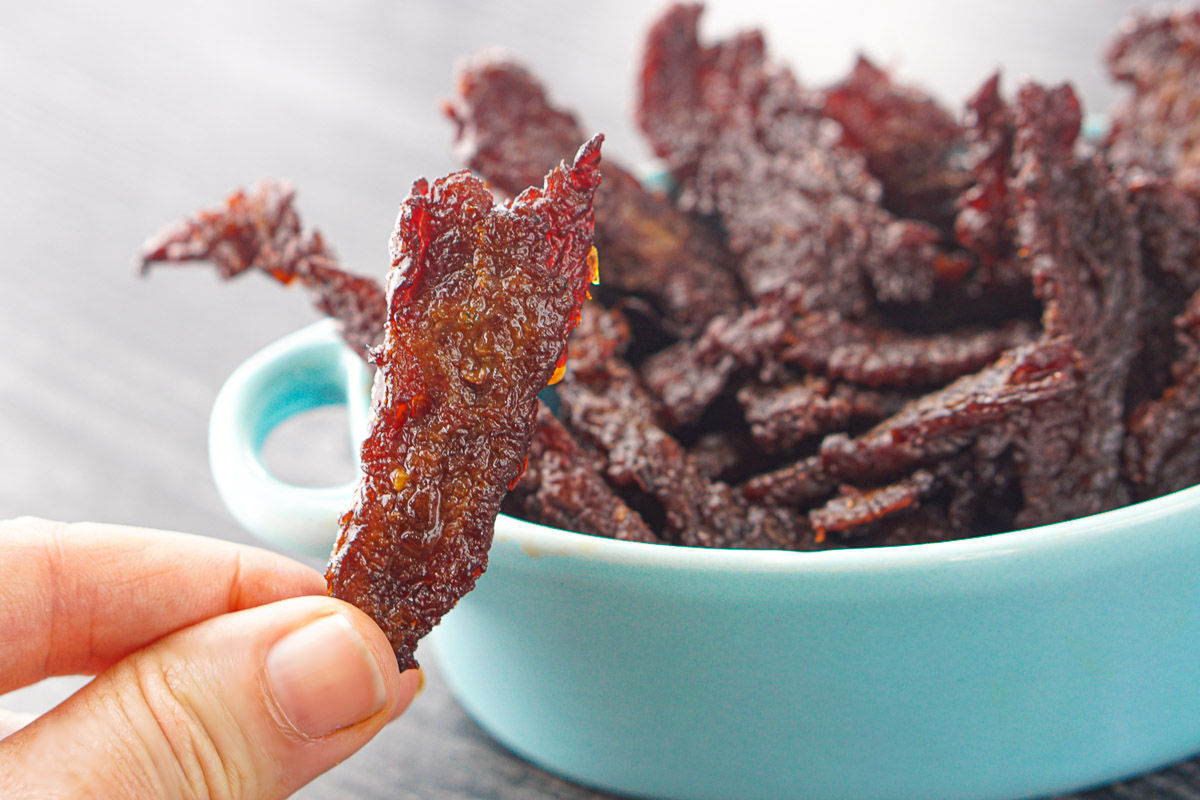 fingers holding a piece of air fryer beef jerky