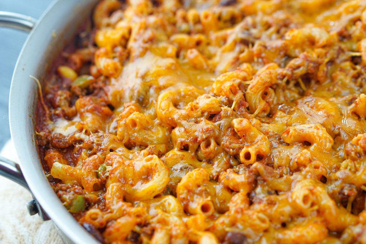 closeup of a pan of cheddar cheese on top of chili macaroni