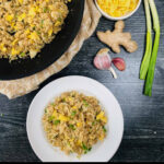 aerial view of a pan and white plate with keto fried rice, garlic, ginger and green onions with text