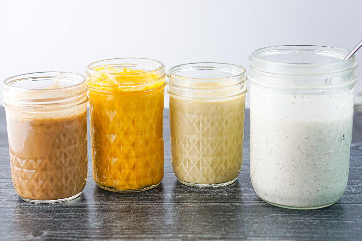 a row of 4 glass mason jars with different homemade dressings