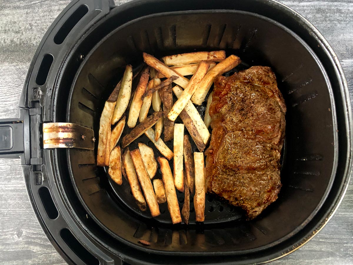 air fryer basket with cooked steak and potatoes