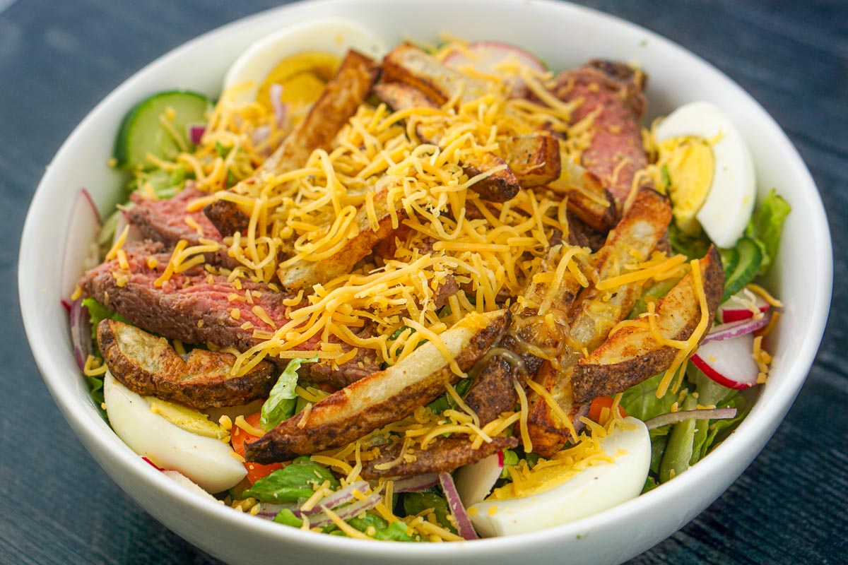 white bowl with a Pittsburgh steak salad topped with cheese