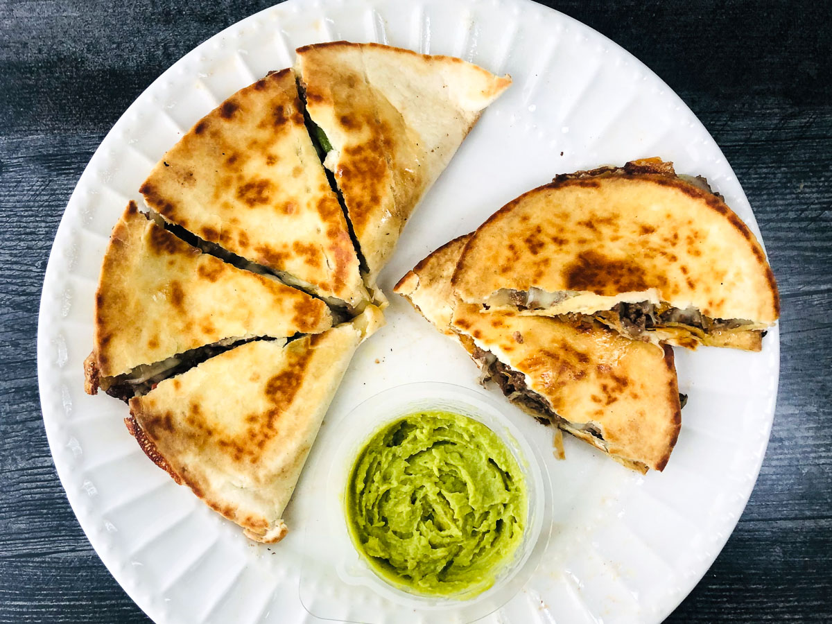 white plate with keto cheesesteak quesadillas and avocado