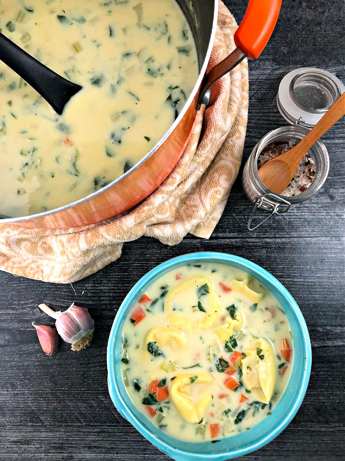 orange pot and aqua bowl with healthy tortellini soup using cauliflower cream