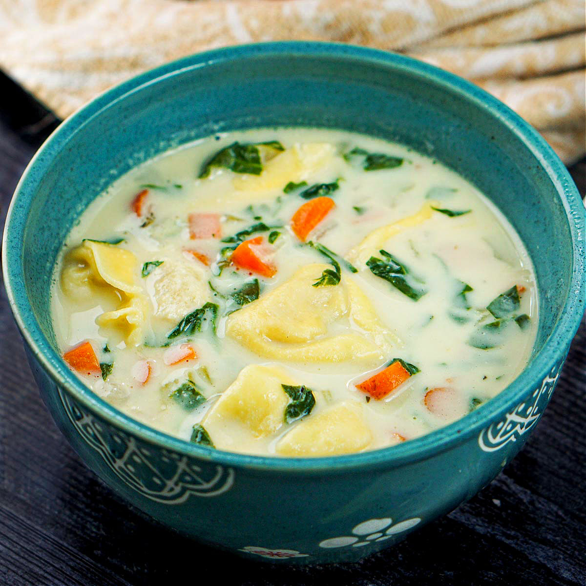 creamy tortellini soup in a teal ceramic bowl