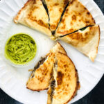 white plate with quesadillas and avocado with text