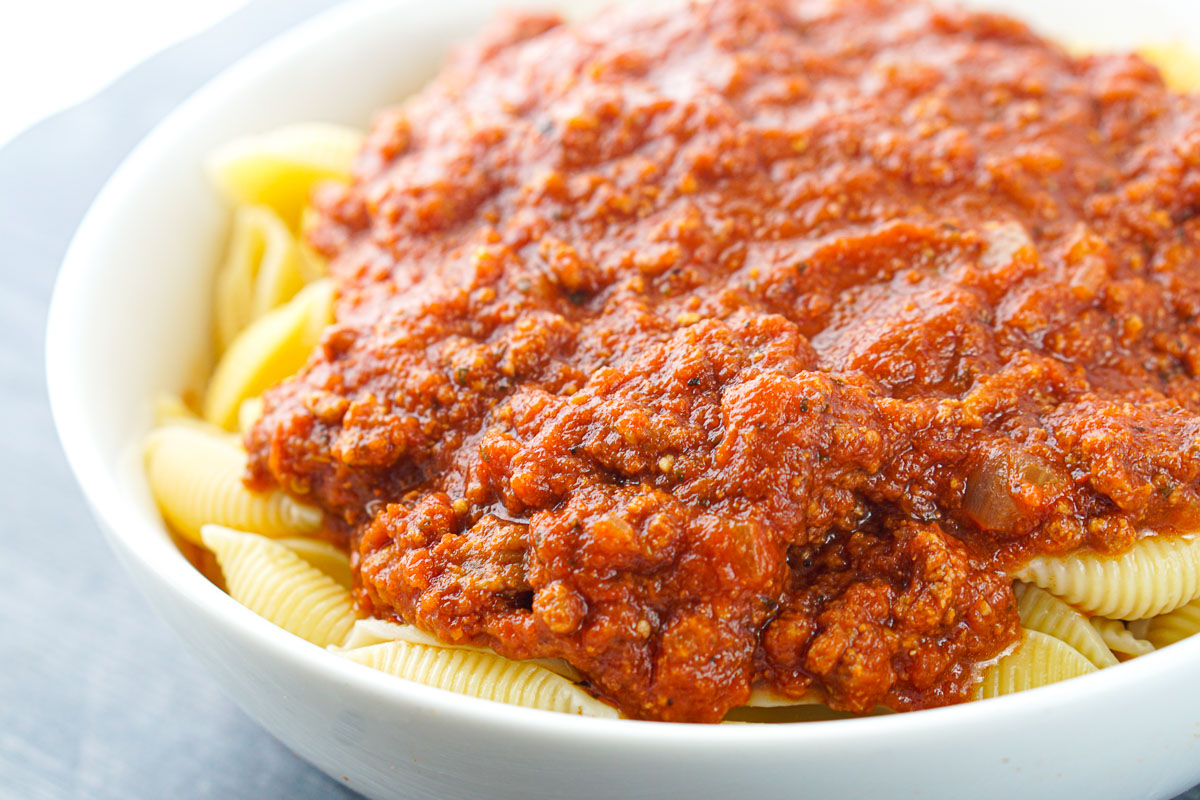 white bowl with shells and meat sauce on top