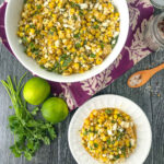 aerial view of white bowl and plate with corn salad and fresh limes and cilantro with text