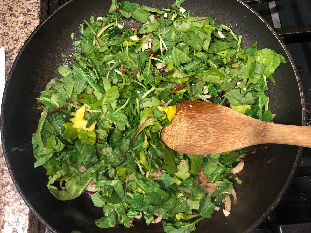 Pan with the greens added to the dish.