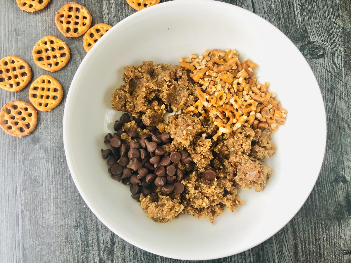 white bowl with ground walnuts and dates, chopped pretzels and chocolate chips