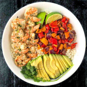 white bowl with grilled keto shrimp, sautéed peppers, cauliflower rice and avocado