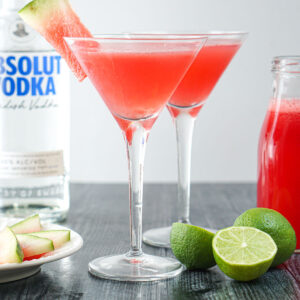 2 watermelon martinis with a bottle of vodka and fresh limes