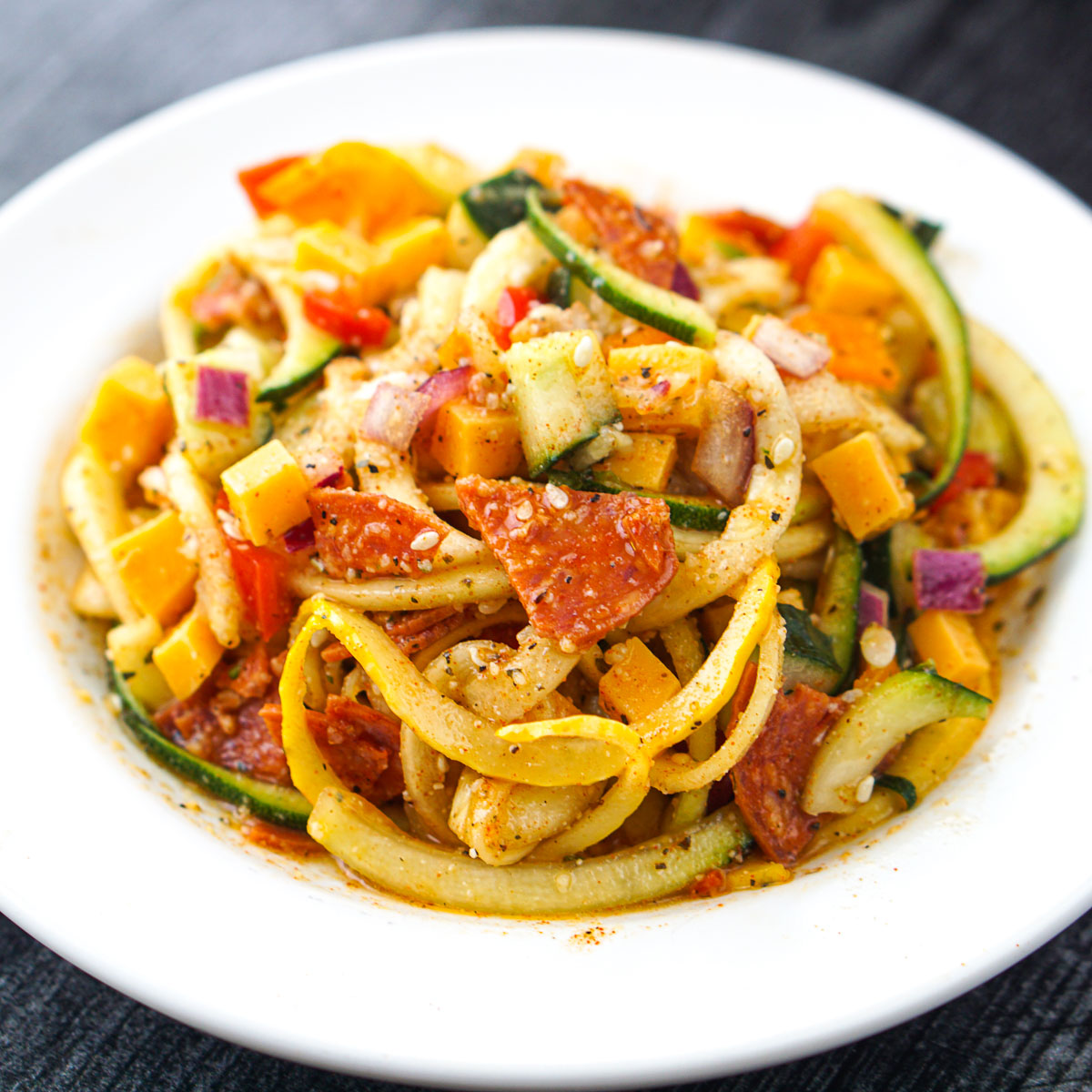 white plate with zucchini pasta salad