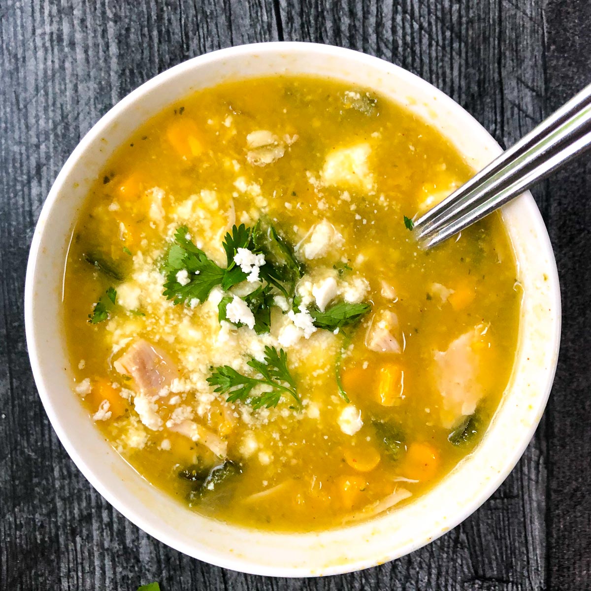 white bowl with poblano corn soup with chicken and a spoon