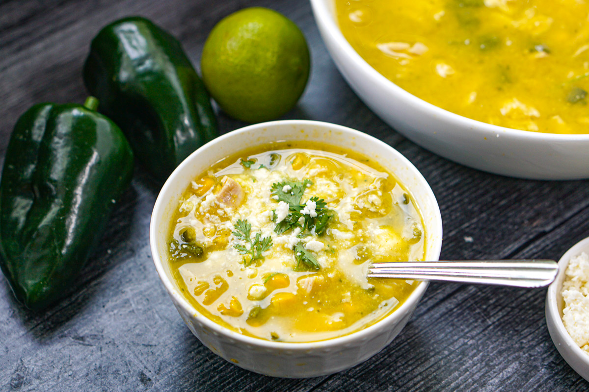 white bowl with chicken and corn poblano soup with fresh cilantro and queso cheese on top