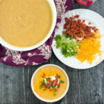 aerial view of a large and small soup bowls with loaded cauliflower soup and a plate of toppings with text