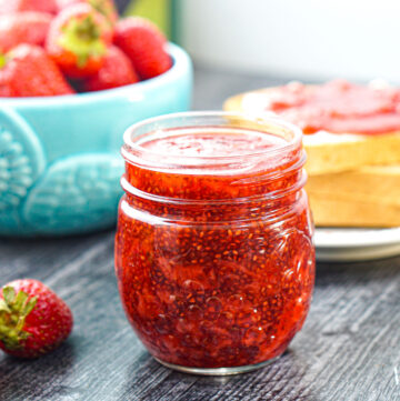 jar of sugar free strawberry chia jam with fresh strawberries in the background