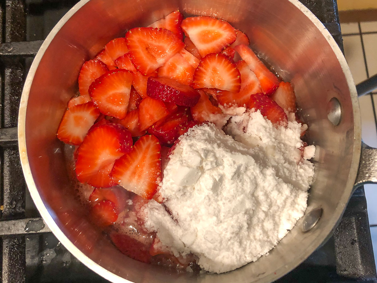pan on the stove with fresh berries and sweetener