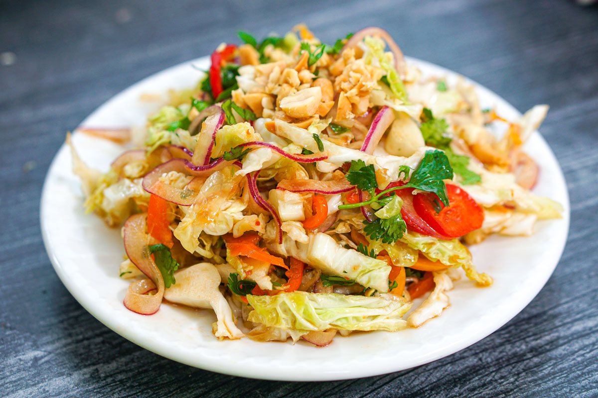 closeup of a white plate with a serving of keto asian salad with cabbage and peanuts