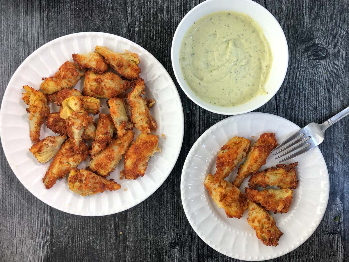 fried keto artichokes on a white plates and avocado dipping sauce