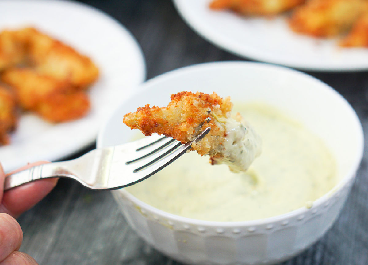 fork with fried artichokes in a dipping sauce